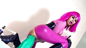 A woman in a wig and a latex suit rides a huge dildo