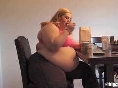 Blonde plumper rubs her belly while eating ice cream