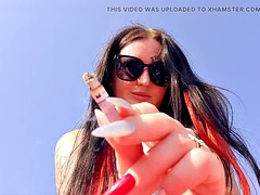Smoking fetish. Dominatrix smokes a cigarette on the beach