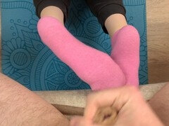 Sporty girl in pink socks does exercises on the mat and gives a footjob to her trainer