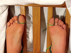 Laugh suppressing of ticklish toetied feet getting brushed