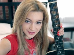 An rectal loving redhead is on the bed, playing with a guitar