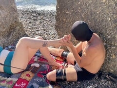 MILF domme Lara enjoys a foot massage from her submissive slave on a public beach