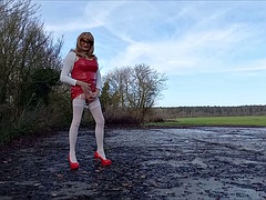 Shemale pees outdoors in a red PVC dress