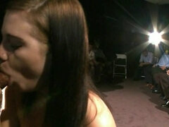 Cute brunette sucks a cock and fucks in front of the crowd