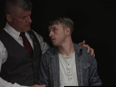 Beefy man in a suit is examining a shy blond fellow