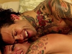 A dude with tattoos is fucking a chick on the bed really well