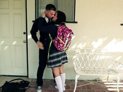 A black haired girl is getting kissed in the yard by her schoolmate