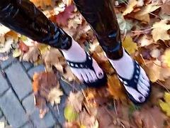 Crossdresser walks in public in latex tights and flip flops on a platform, showing off her sexy feet.