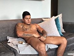 Our solo of the week is Eric, a big, muscular Latino with a serious expression. Sitting on the couch, he quickly undresses.