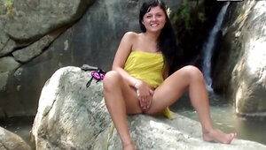 Brunette Bella Margo poses naked by the waterfall and masturbates