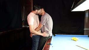 Two men with big cocks are banging a lad on the table