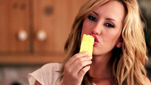 A blonde is on the kitchen counter, fooling around with some food