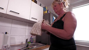 Old blonde woman is fucking herself in the kitchen