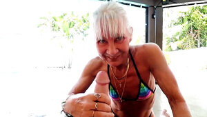 GILF gives a blowjob and a handjob in a poolside video