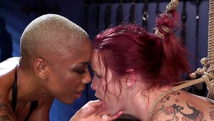 Ebony domme in leather top turns the redhead into her slave