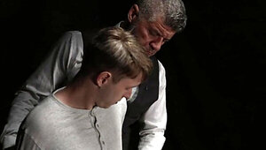 Beefy man in a suit is examining a shy blond fellow