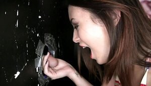 Brunette is pulling a large cock inside a glory hole in the dark room