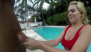 A blonde is sucking a big pecker by the pool outside on a warm day