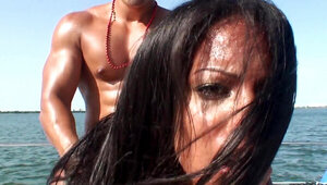 A dark babe is on a boat and she is doing it doggy style there
