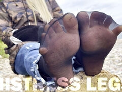 Sexy feet in black nylon socks wiggling toes at the seashore