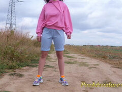 Hipster girl with a hoodie pee trough her jeans and pee next to the wheel of the car