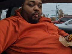 Fat guy in a small car eating McDonalds.