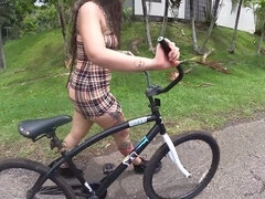 Biker girl with a butt plug rides her bike on the street, catching the attention of a horny driver